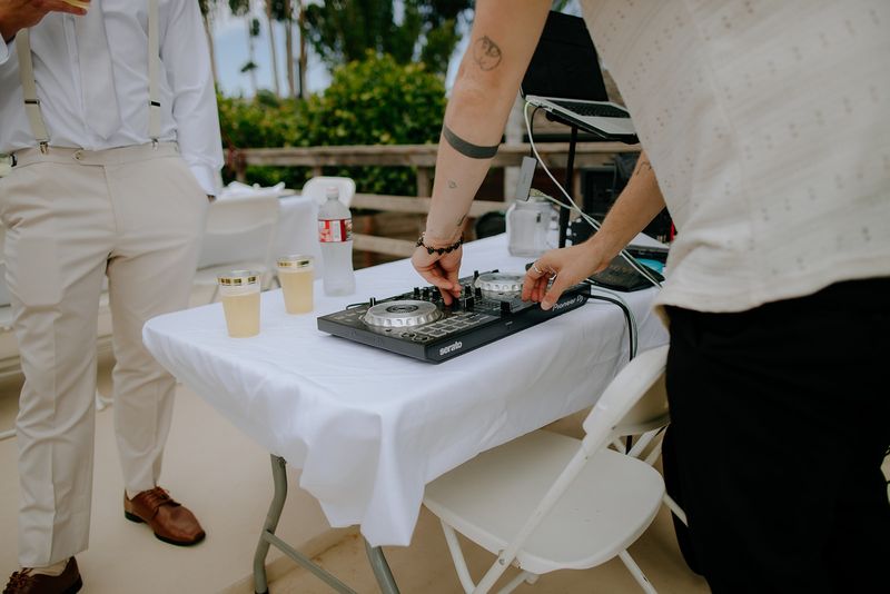 Close-up of Max's hands on a DJ controller at a sunny outdoor reception